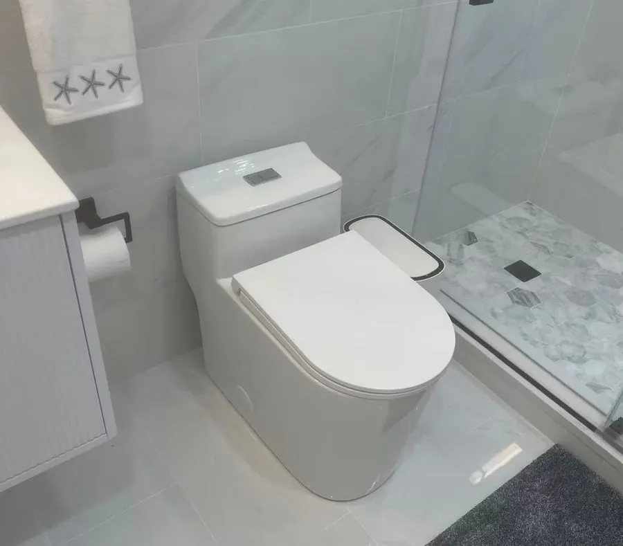 Finished bathroom remodel with a one piece toilet and marble tile shower