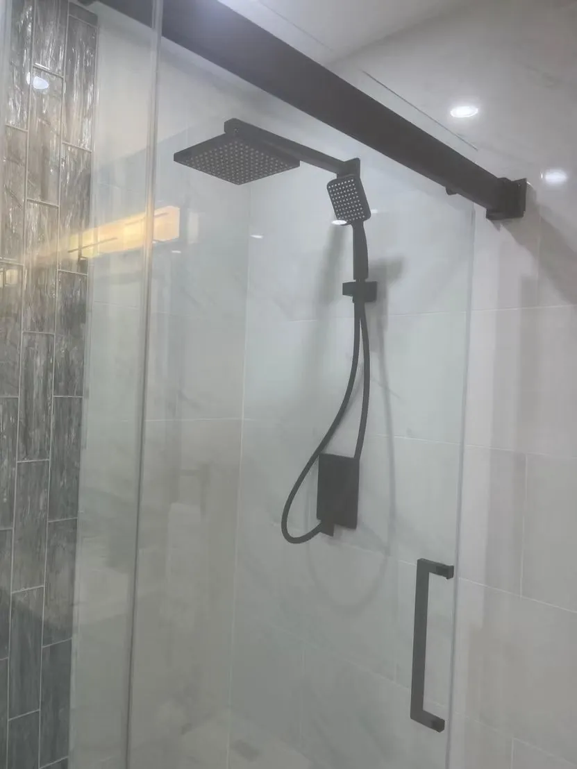 Glass shower with a matte black rain shower system, installed by Abreu