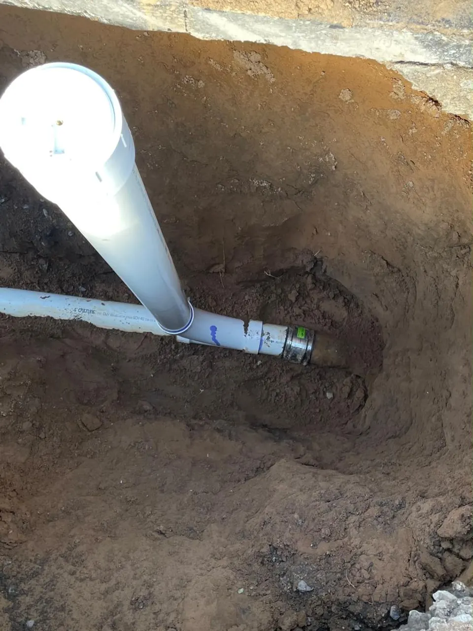 New PVC cleanout riser tied into the sewer line in an open excavation