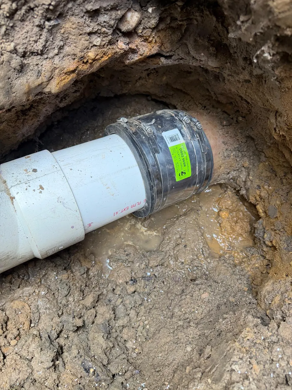 Shielded rubber coupling joining the existing sewer pipe to new PVC